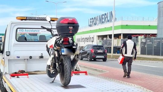 Motocykl na lawecie, a kierujący z reklamówką do domu na piechotę