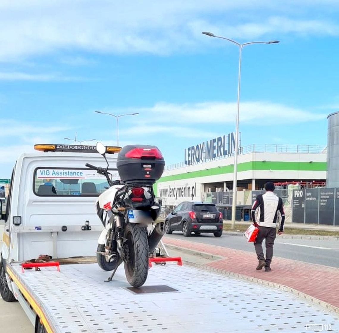 Motocykl na lawecie, a kierujący z reklamówką do domu na piechotę