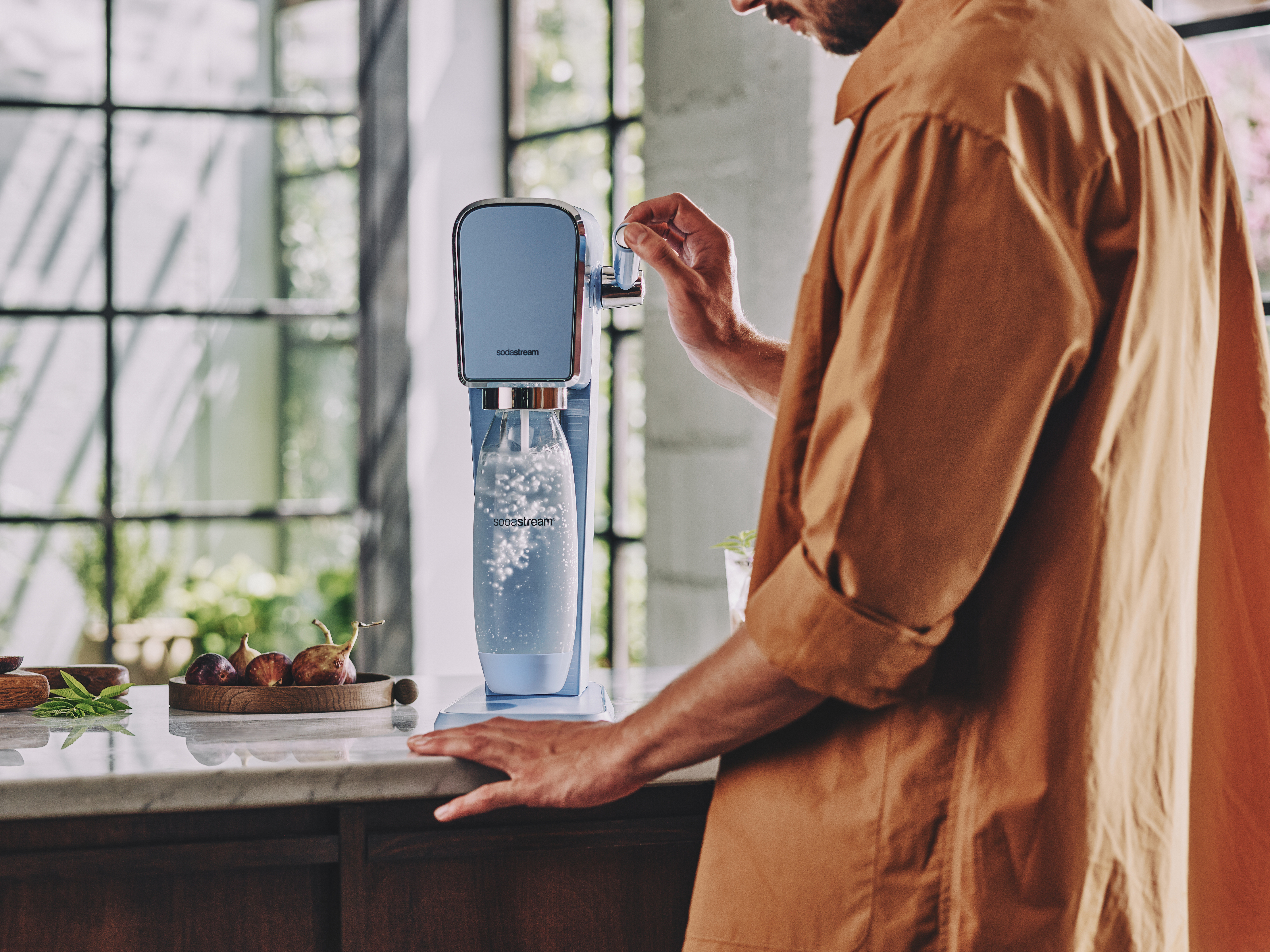 Mężczyzna gazujący wodę w saturatorze Art SodaStream.